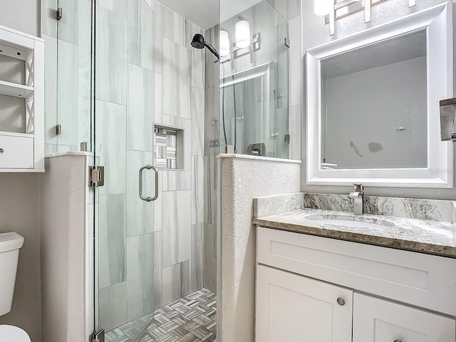 bathroom with a shower with door, vanity, and toilet