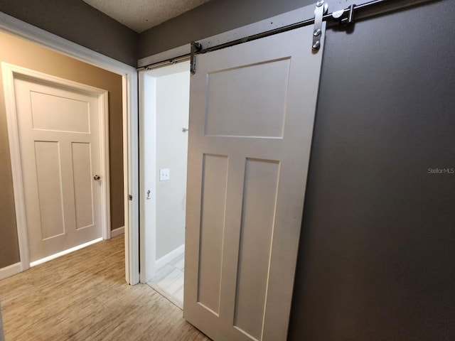 corridor featuring a barn door and light hardwood / wood-style floors