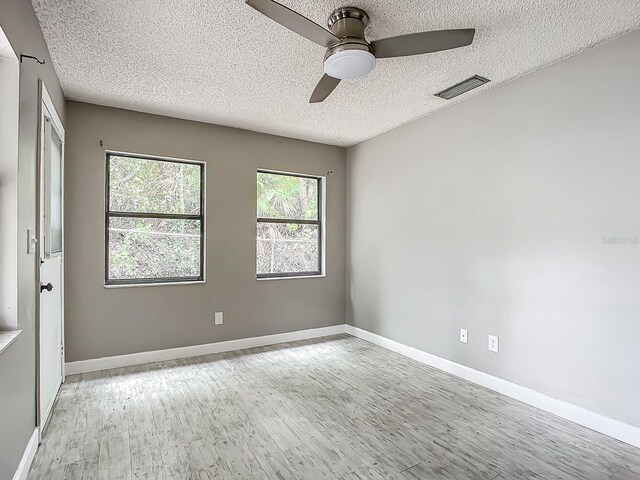 spare room with ceiling fan, light hardwood / wood-style flooring, and a textured ceiling