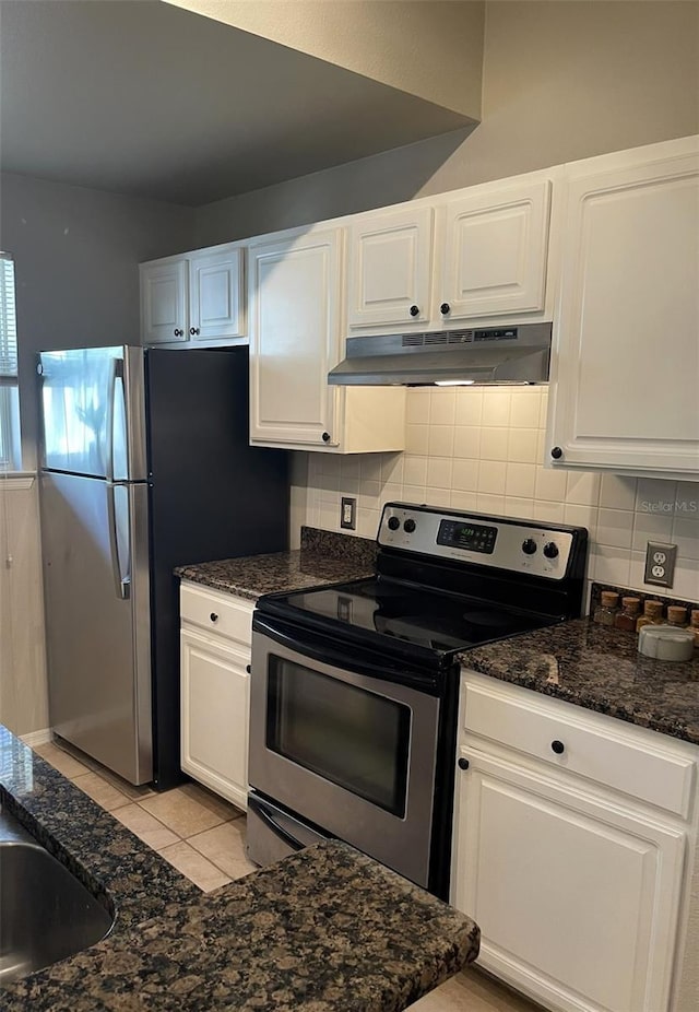 kitchen featuring decorative backsplash, light tile patterned floors, white cabinetry, appliances with stainless steel finishes, and dark stone countertops