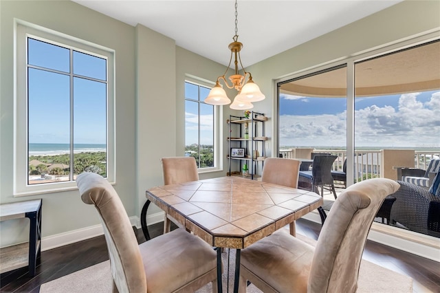 dining room with dark hardwood / wood-style flooring, a water view, and a chandelier