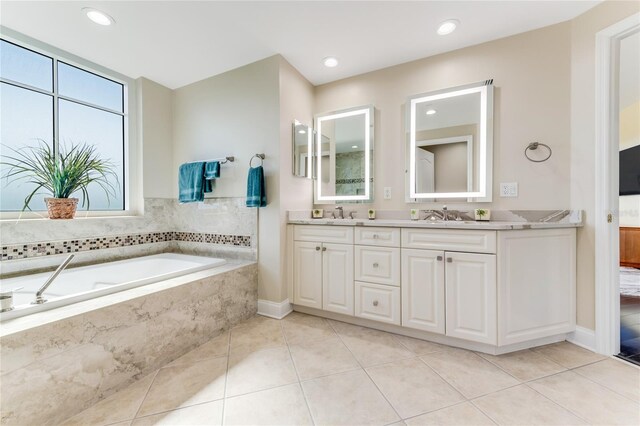 bathroom featuring a relaxing tiled tub, vanity, and tile patterned floors