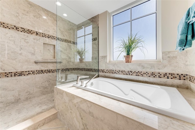 bathroom featuring a relaxing tiled tub and tile walls