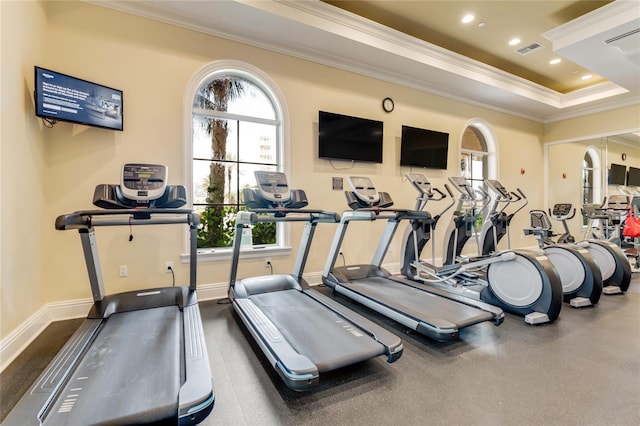 gym featuring ornamental molding and a raised ceiling