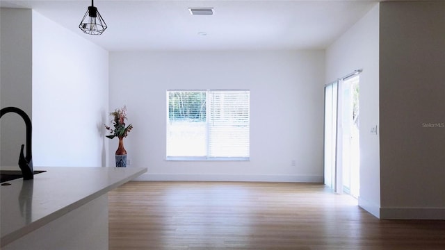 unfurnished dining area featuring hardwood / wood-style flooring and a notable chandelier