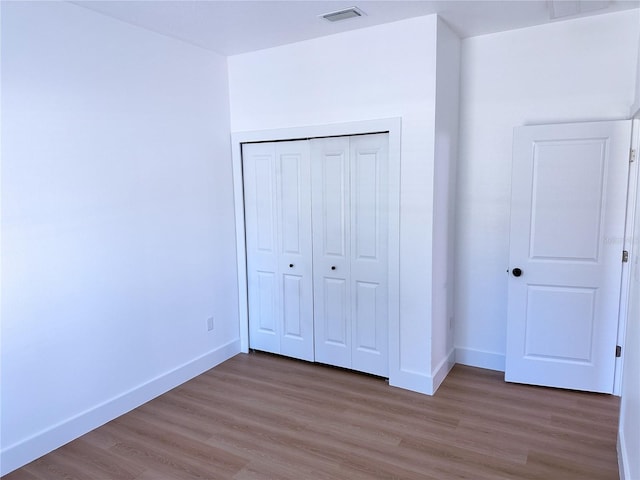 unfurnished bedroom with wood-type flooring and a closet