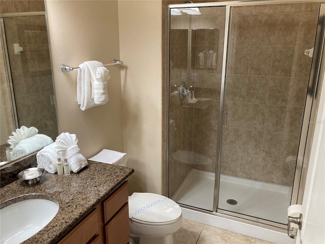 bathroom featuring toilet, a shower with shower door, vanity, and tile patterned floors