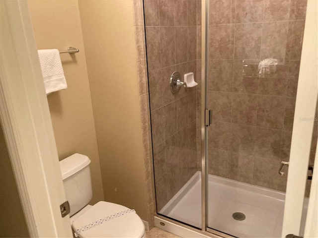 bathroom with a shower with door and toilet