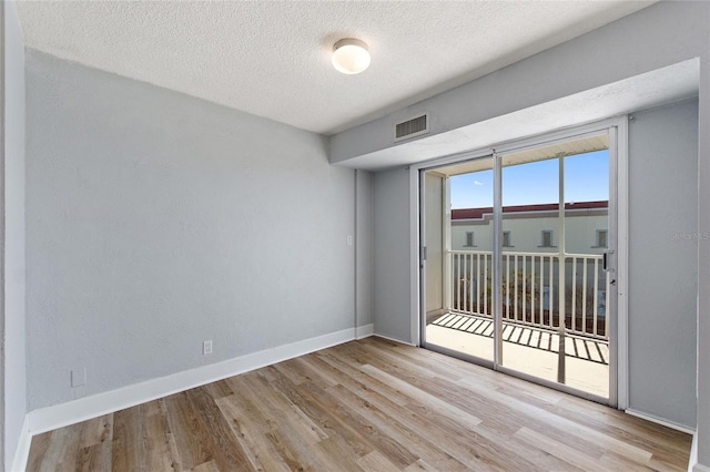 spare room featuring a textured ceiling and light wood-type flooring