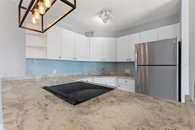 kitchen with a sink, decorative backsplash, open shelves, black electric stovetop, and freestanding refrigerator