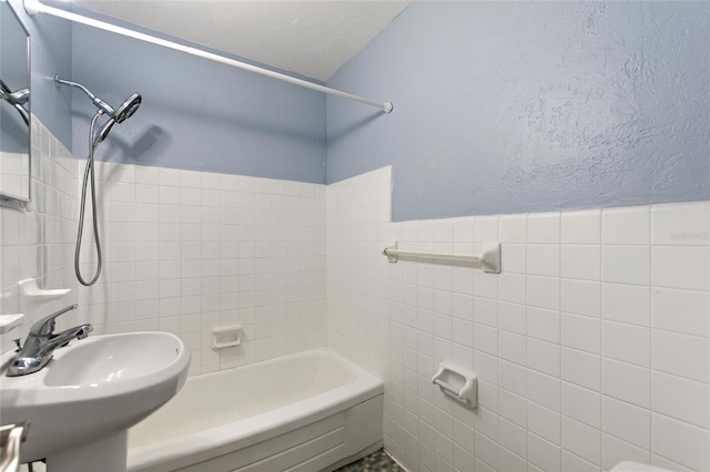 full bathroom with tile walls, wainscoting, shower / washtub combination, and a sink