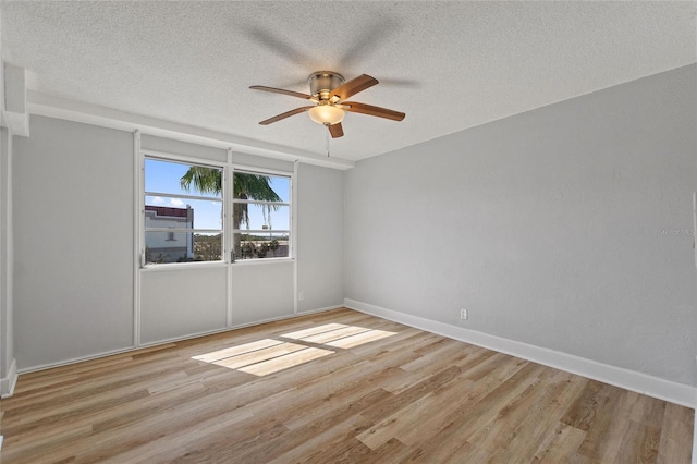spare room featuring light wood-type flooring, ceiling fan, and a textured ceiling
