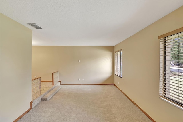 empty room with a textured ceiling and light colored carpet