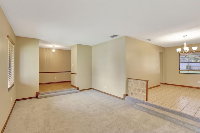 spare room with a notable chandelier and light colored carpet