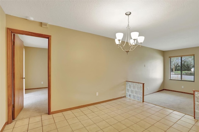 carpeted spare room featuring a textured ceiling and an inviting chandelier