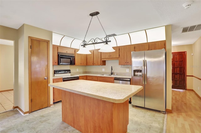 kitchen featuring sink, black appliances, hanging light fixtures, and a kitchen island