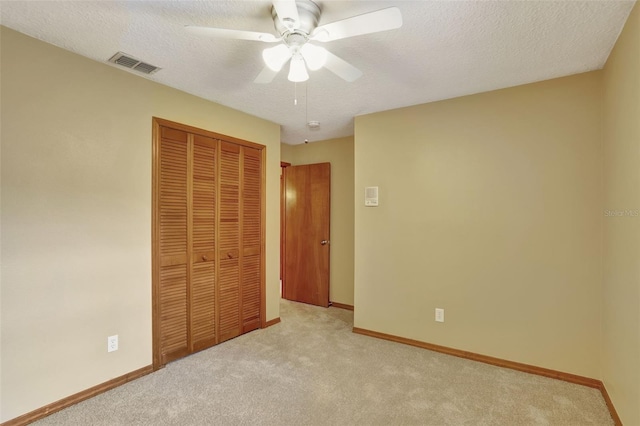 unfurnished bedroom with a closet, ceiling fan, a textured ceiling, and light colored carpet