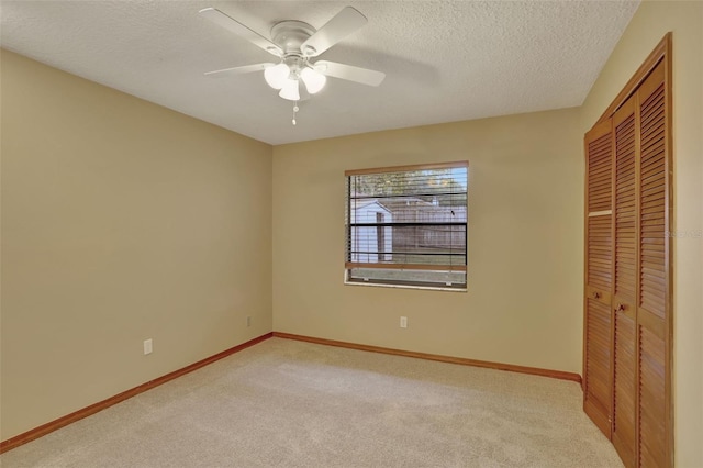 unfurnished bedroom with light carpet, a textured ceiling, a closet, and ceiling fan