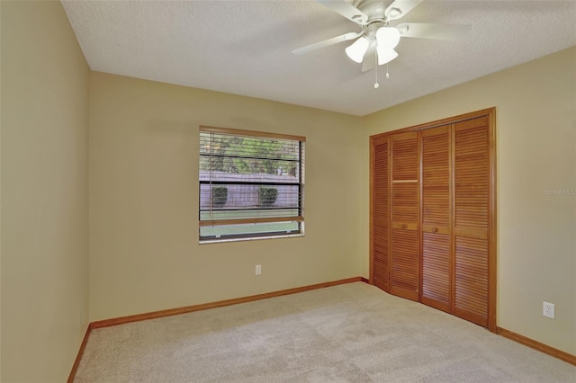 unfurnished bedroom with a closet, ceiling fan, a textured ceiling, and light colored carpet