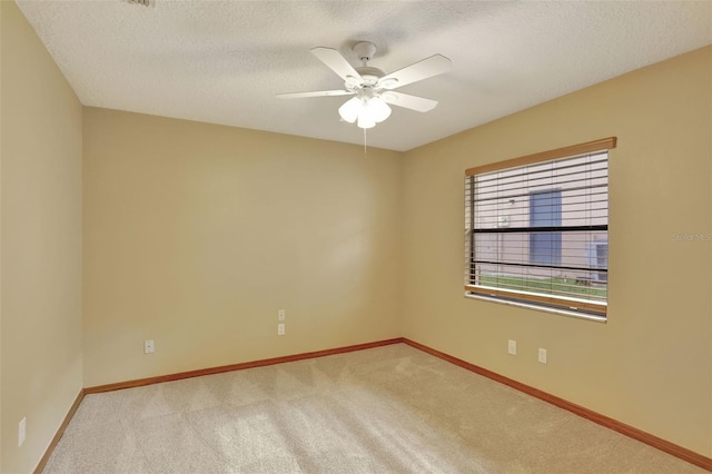 empty room with light carpet, a textured ceiling, and ceiling fan