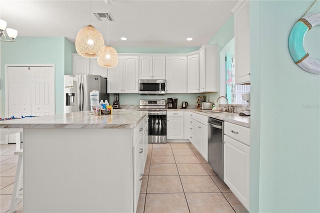 1055 Lake Berkley Dr, Kissimmee, FL 34746 - kitchen featuring appliances with stainless steel finishes, a center island, light tile patterned floors, white cabinets, and pendant lighting