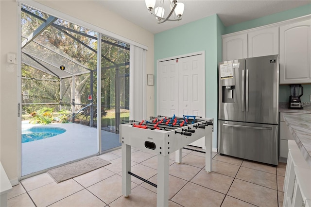 1055 Lake Berkley Dr, Kissimmee, FL 34746 - kitchen featuring stainless steel refrigerator with ice dispenser, white cabinetry, light tile patterned floors, and hanging light fixtures
