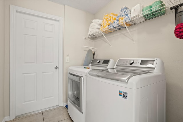 clothes washing area with light tile patterned floors, washing machine and dryer, and a textured ceiling