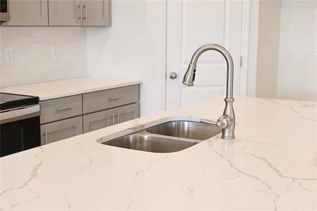 kitchen featuring gray cabinetry, light stone countertops, sink, electric stove, and decorative backsplash