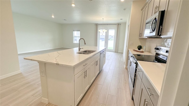 kitchen with an island with sink, light hardwood / wood-style flooring, stainless steel appliances, sink, and light stone countertops