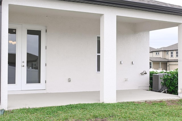 view of exterior entry with a patio area, french doors, and central AC unit