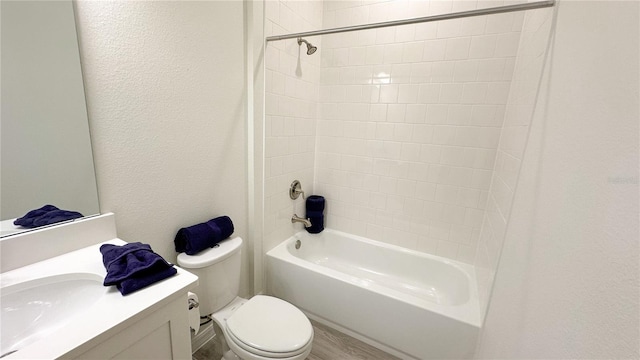 full bathroom featuring tiled shower / bath, vanity, wood-type flooring, and toilet