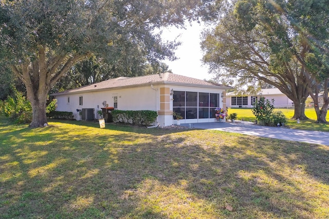 view of home's exterior with central air condition unit, a sunroom, a lawn, and a patio