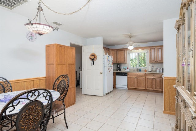 kitchen with wooden walls, hanging light fixtures, light tile patterned flooring, white appliances, and ceiling fan