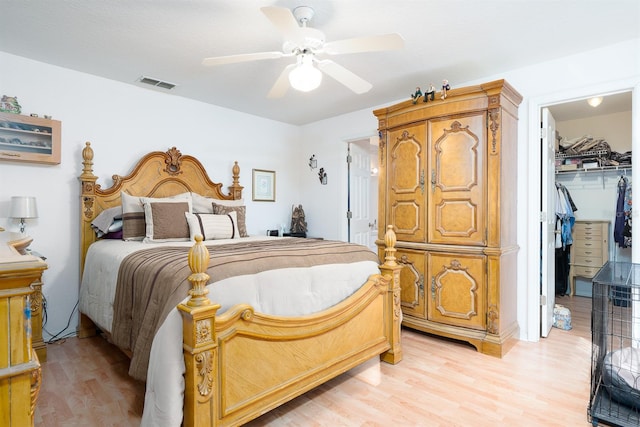 bedroom with light hardwood / wood-style flooring, a walk in closet, a closet, and ceiling fan