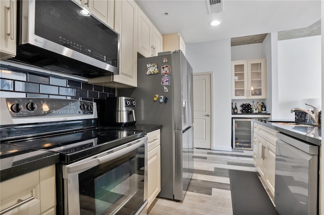 kitchen featuring stainless steel appliances, wine cooler, sink, light hardwood / wood-style floors, and tasteful backsplash