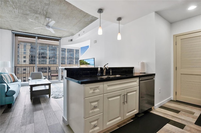 kitchen featuring hanging light fixtures, sink, light wood-type flooring, white cabinets, and ceiling fan