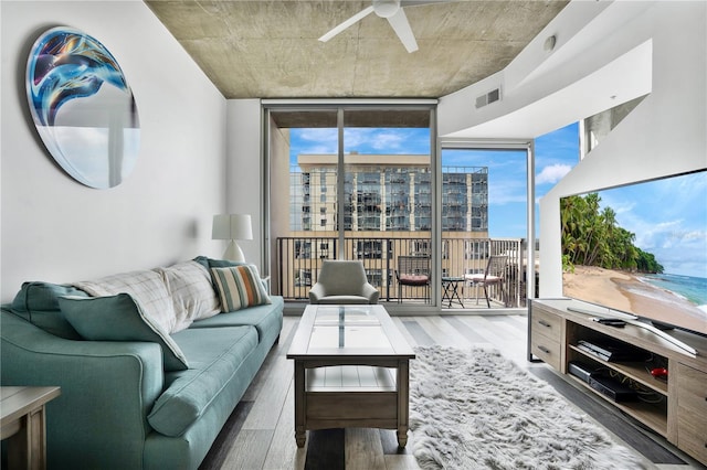 living room with ceiling fan, hardwood / wood-style flooring, expansive windows, and plenty of natural light