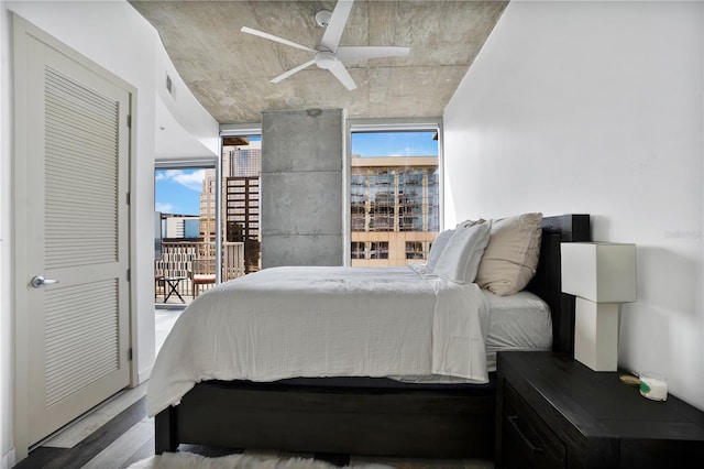 bedroom featuring ceiling fan, wood-type flooring, multiple windows, and access to exterior