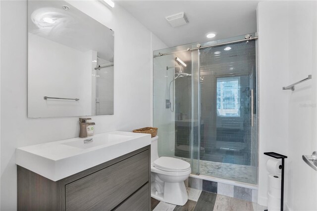 bathroom featuring vanity, toilet, and a shower with door