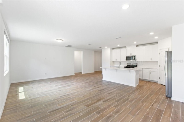 kitchen featuring white cabinetry, sink, backsplash, a center island with sink, and appliances with stainless steel finishes