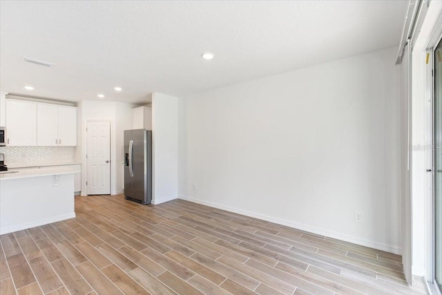 kitchen featuring white cabinets, appliances with stainless steel finishes, backsplash, and light hardwood / wood-style flooring