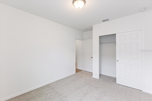 unfurnished bedroom with light colored carpet and a closet