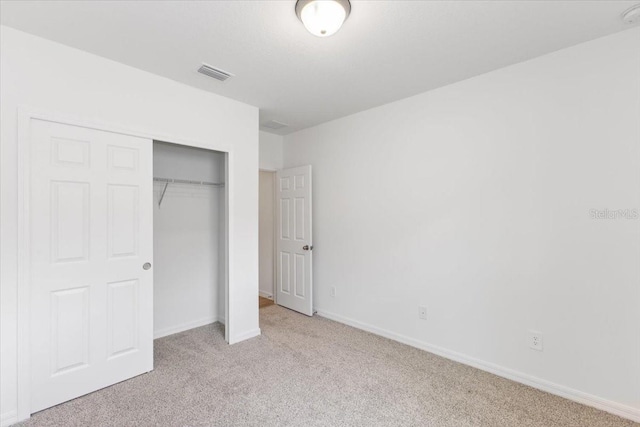 unfurnished bedroom featuring light carpet and a closet