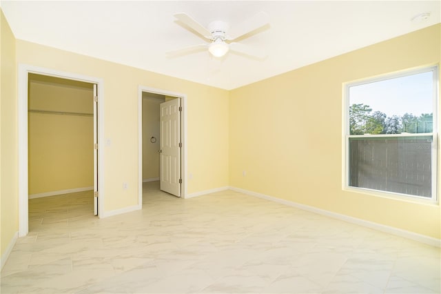 unfurnished bedroom with a walk in closet, a closet, and ceiling fan