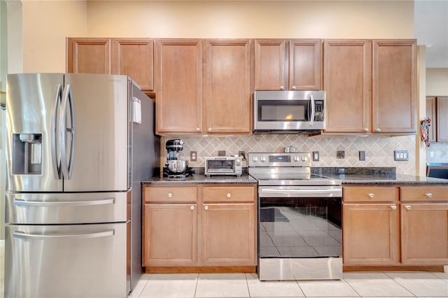 kitchen with stainless steel appliances, dark stone countertops, and backsplash