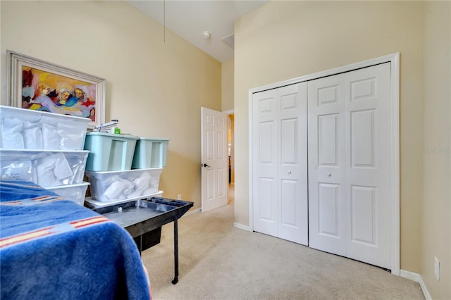 carpeted bedroom with a closet and high vaulted ceiling