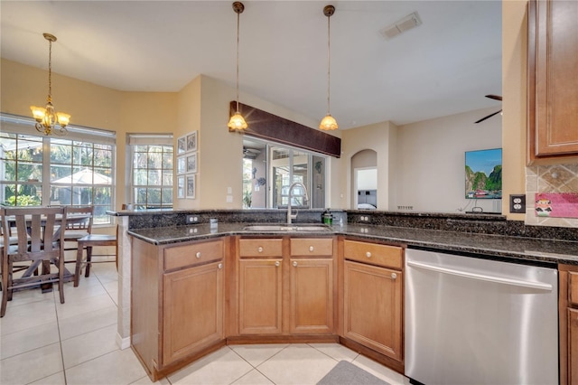 kitchen featuring dishwasher, pendant lighting, dark stone counters, and sink