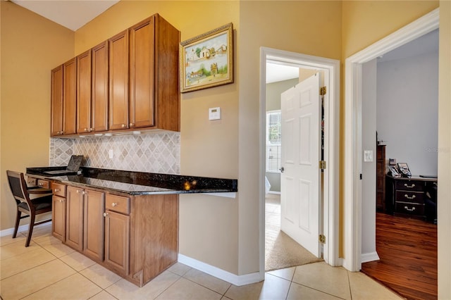 kitchen with dark stone countertops, decorative backsplash, and light tile patterned floors