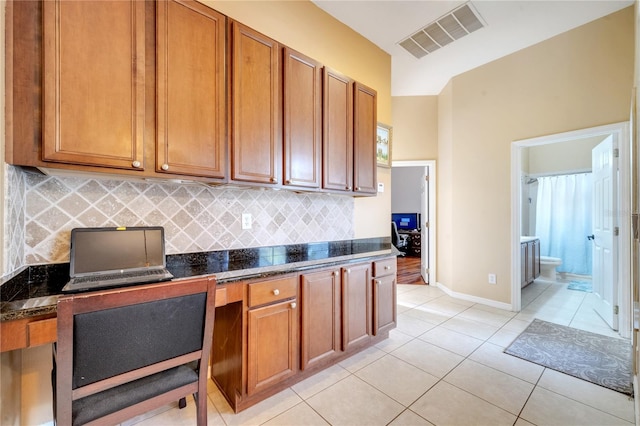 kitchen featuring dark stone counters, backsplash, and light tile patterned floors