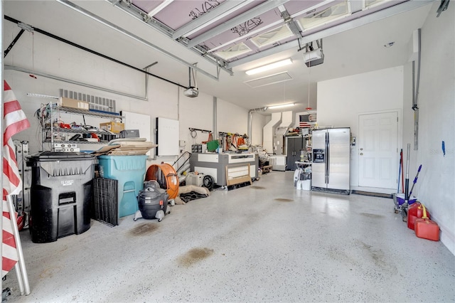 garage with stainless steel fridge with ice dispenser and a garage door opener